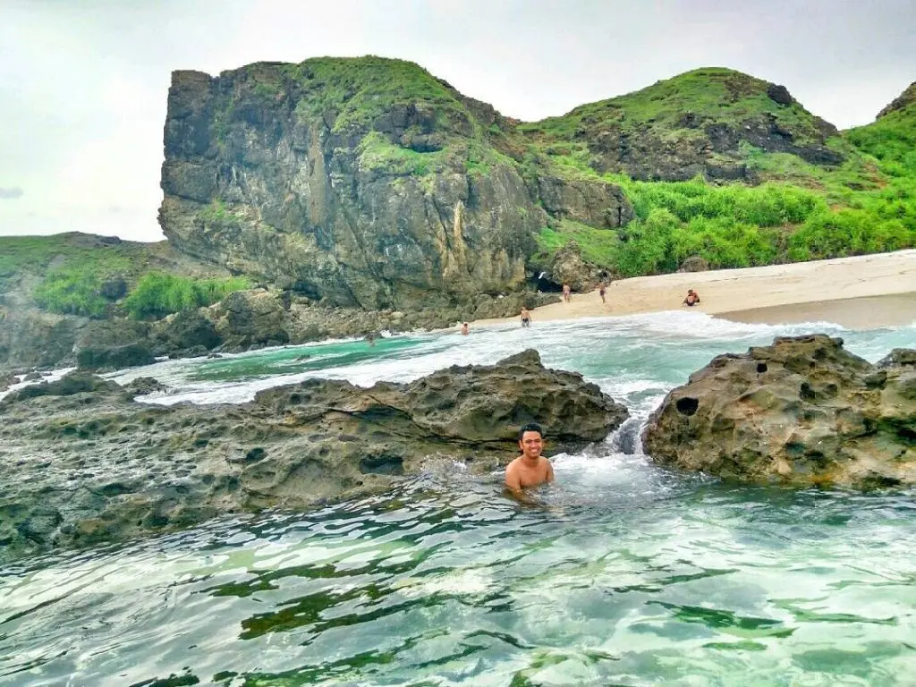 Swimmer in a natural rock pool beside the beach